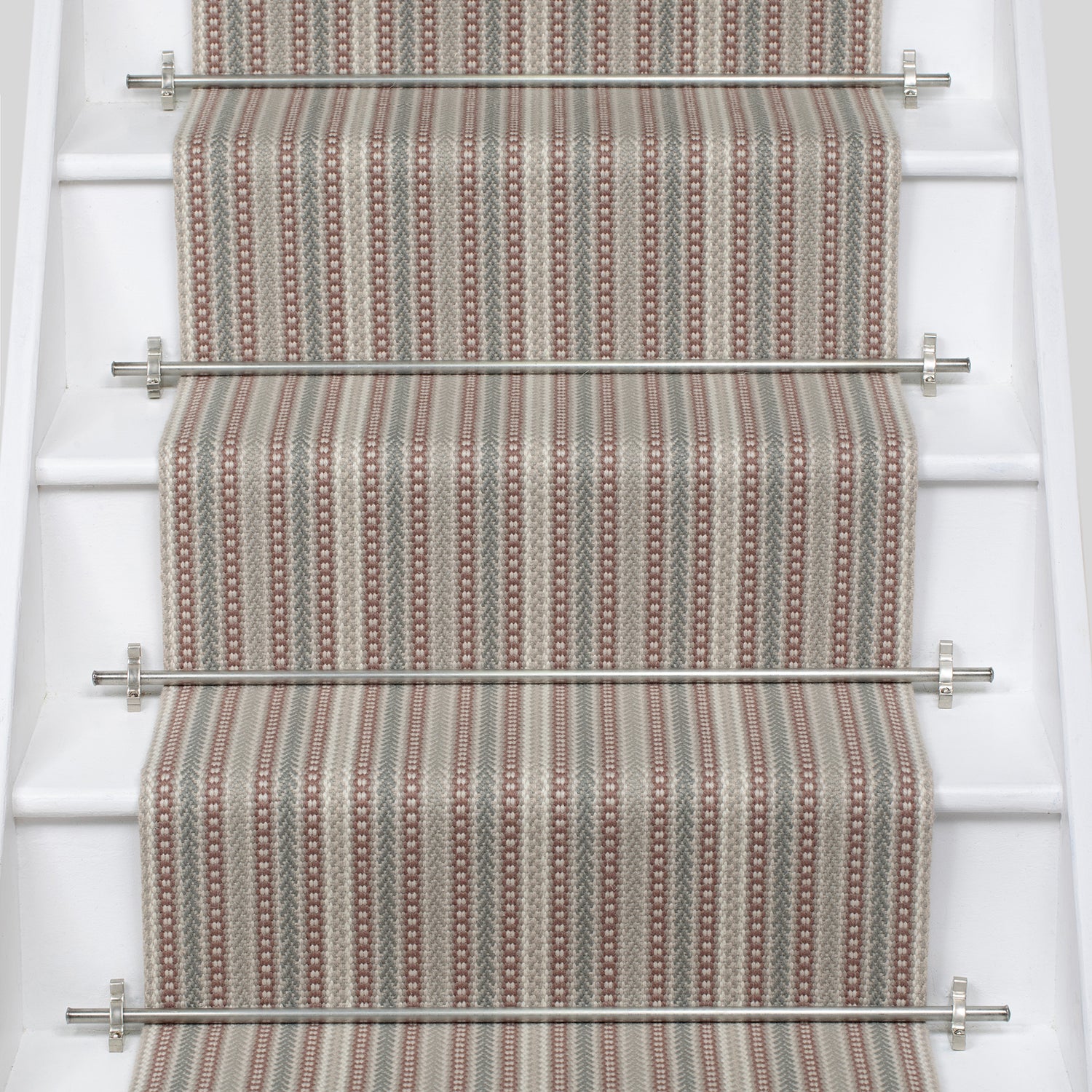 White stair case with a runner in a complex woven stripe design of wool in shades of pink and grey.