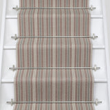White stair case with a runner in a complex woven stripe design of wool in shades of pink and grey.