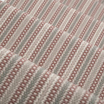 Detail of a stair runner in a complex woven stripe design of wool in shades of pink and grey.