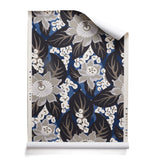 A roll of tropical floral wallpaper featuring grey colored blossoms with cream centers, black leaves on rich blue background. 