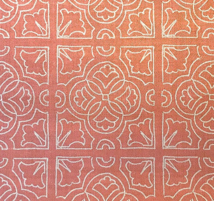 Detail of fabric in a damask lattice print in white on a coral field.