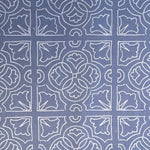 Detail of fabric in a damask lattice print in white on a blue field.