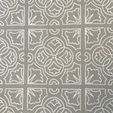 Detail of fabric in a damask lattice print in white on a gray field.