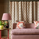 Patterned sofa with decorative pillows in a room with a lamp and floral arrangement.