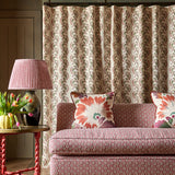Patterned sofa with decorative pillows in a room with a lamp and floral arrangement.