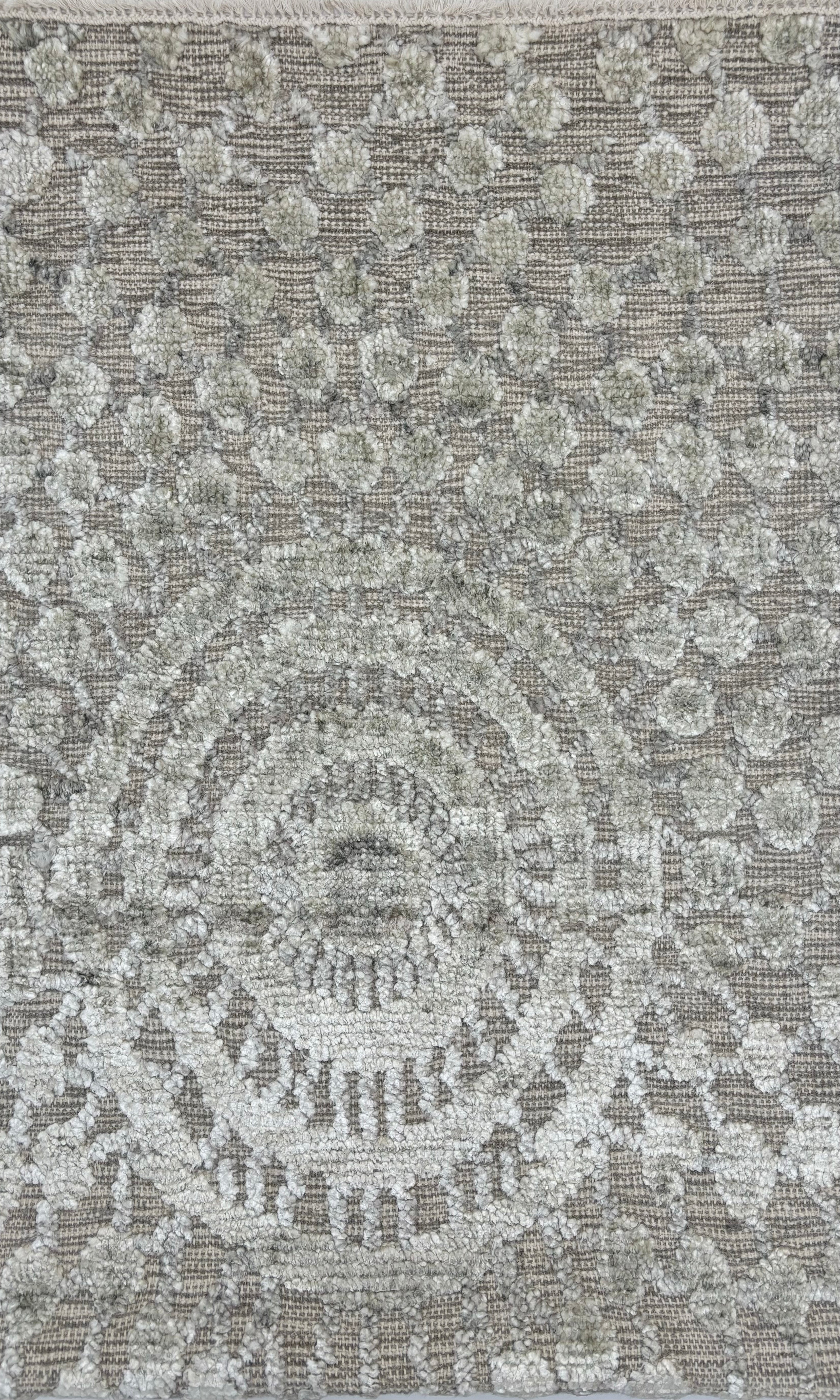 Handknotted wool rug in a raised circular compass design in shades of grey. 