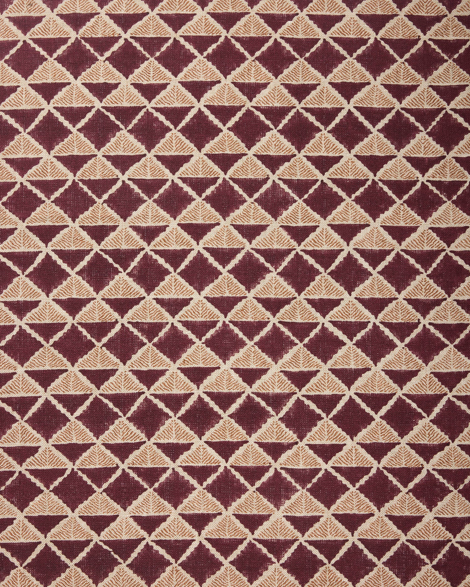 Fabric with a geometric pattern of triangles in wine purple and brown.