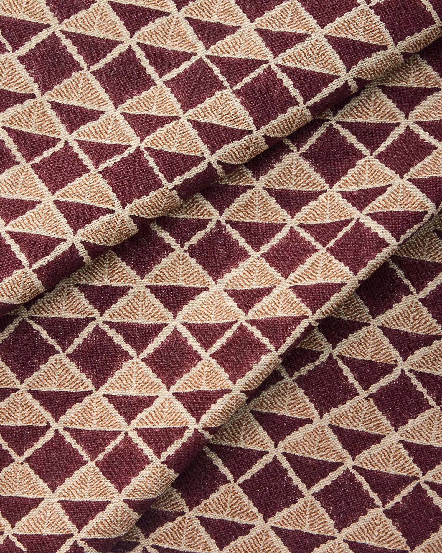 Draped fabric with a geometric pattern of triangles in wine purple and brown.