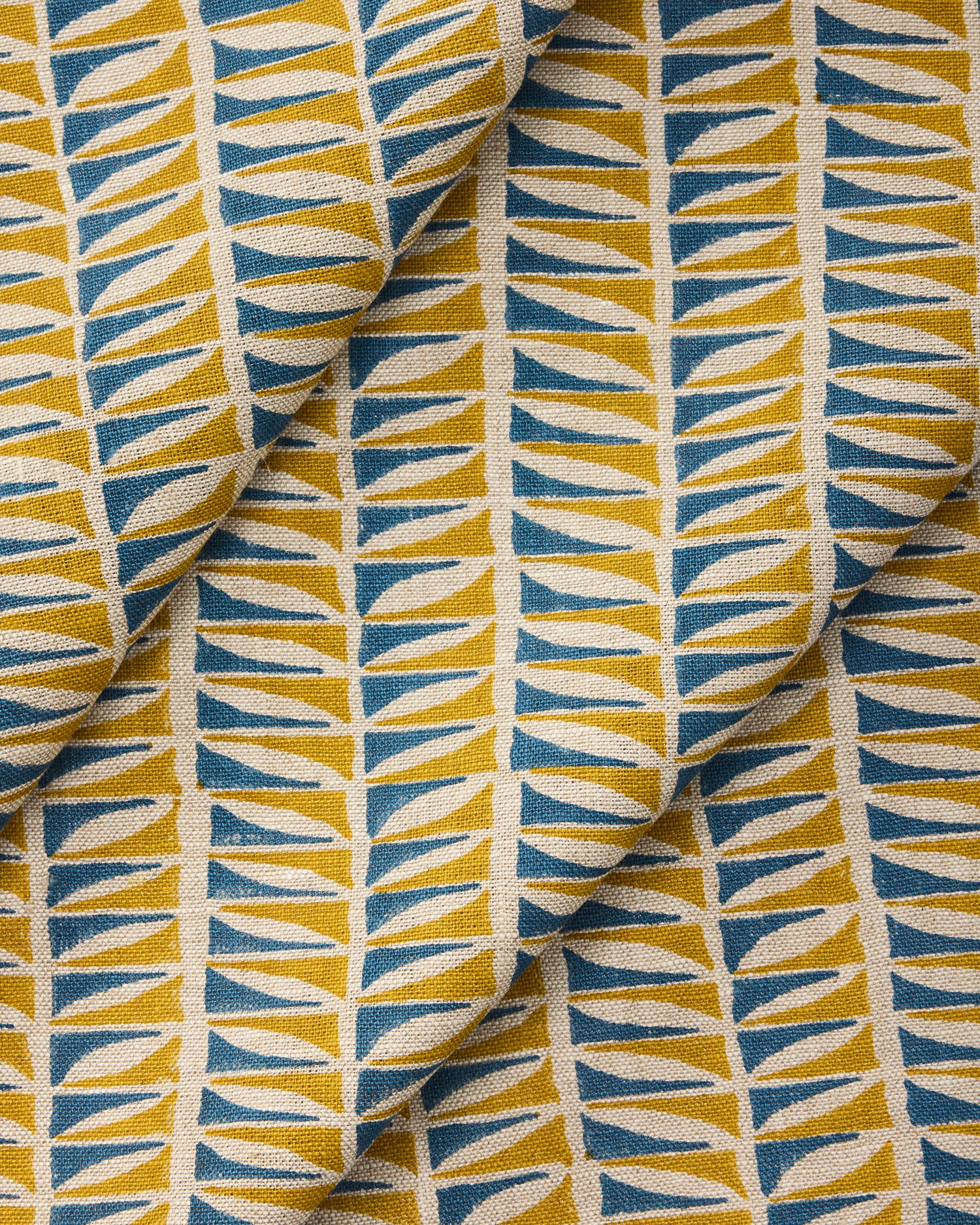 Draped close-up of fabric with a geometric leaf pattern in blue and ochre.