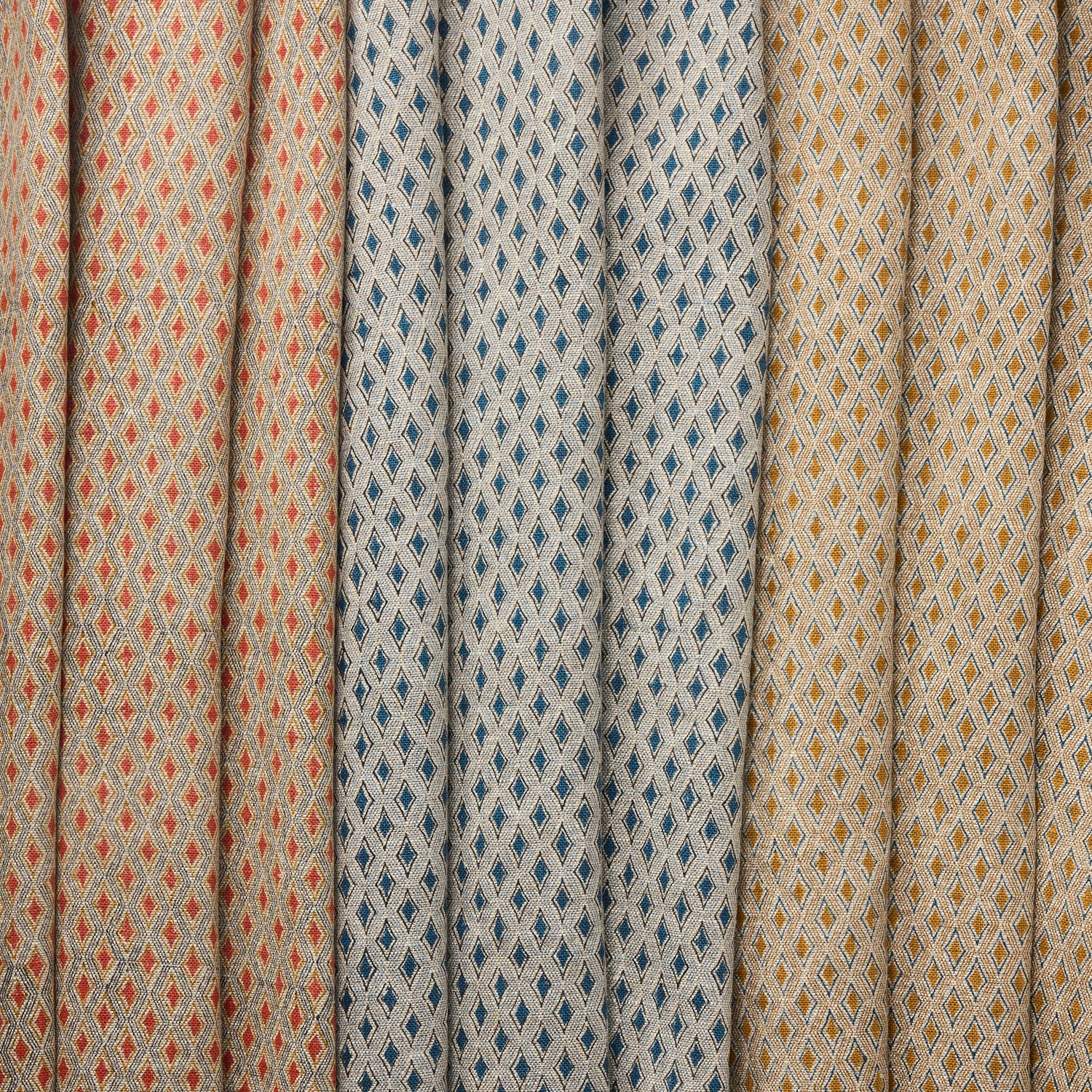 Three fabric swatches diamond pattern in red, blue and tan.