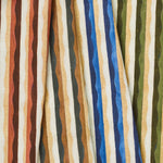 A group of draped woven fabrics, each in a different colorway of a curvy hand-painted stripe pattern.