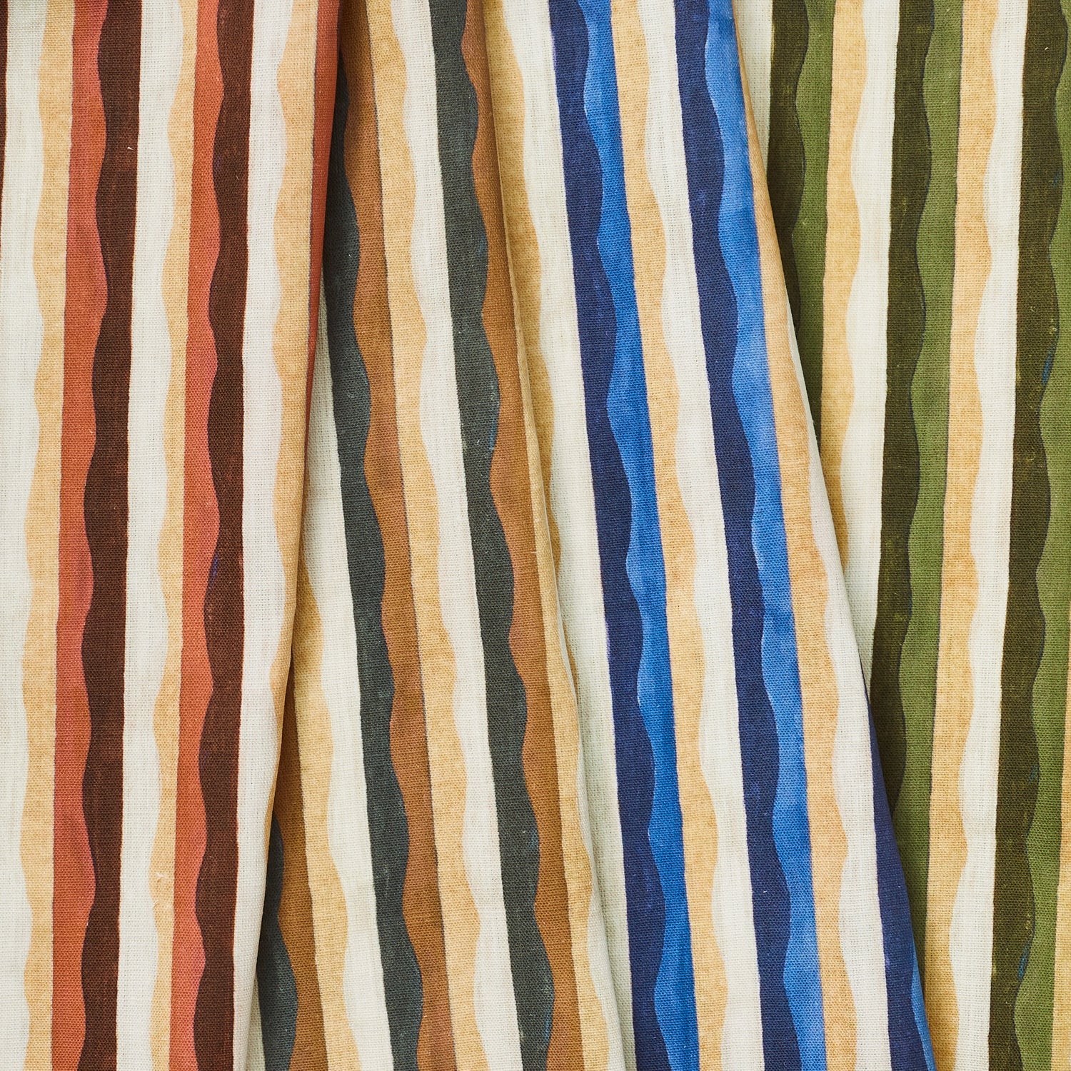 A group of draped woven fabrics, each in a different colorway of a curvy hand-painted stripe pattern.