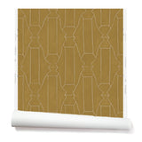 Partially unrolled wallpaper in a repeating curvolinear print in cream on a painted gold field.