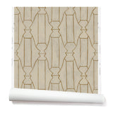 Partially unrolled wallpaper in a repeating curvolinear print in rust on a painted cream field.