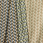 A group of draped woven fabrics, each in a different colorway of a repeating mosaic print.