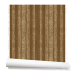 A partially unrolled roll of wallpaper in a striped pattern of intricate white lines over a rich rust brown background.