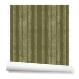 A partially unrolled roll of wallpaper in a striped pattern of intricate white lines over a deep olive green background.