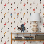 A table with books and a lamp in front of a wall papered in a pattern of Japanese soldiers carrying flags on a cream background.