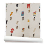 A roll of wallpaper with a pattern of hand-drawn Japanese soldiers carrying various geometric flags, on a parchment-colored background.