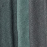 A group of folded linen swatches in various shades of dark green and gray.