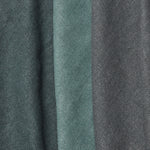 A group of folded linen swatches in various shades of dark green and gray.