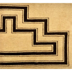 Detail of a handknotted rug with a geometric stripe pattern in brown on a cream field.