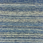 Detail of a wool rug with a textural strié stripe pattern in indigo and cream