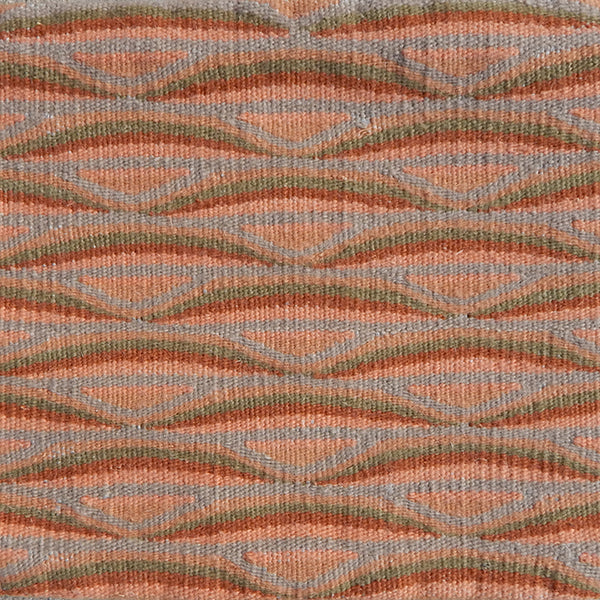 Detail of handwoven rug in a wavy striped pattern in shades of orange