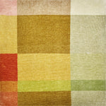 Detail of a handknotted rug in a graphic geometric design in layered shades of a green, tan, ochre and orange.