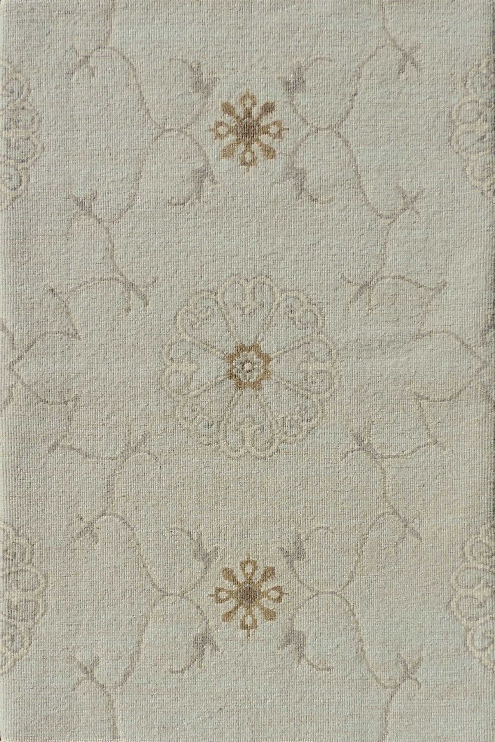 Close up of hand woven rug in a floral filigree pattern in grey, tan and cream on a pastel aqua blue field.