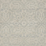 Close up of a handwoven rug in an ornate damask medallion design in cream on a grey field. 