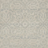 Close up of a handwoven rug in an ornate damask medallion design in cream on a grey field. 