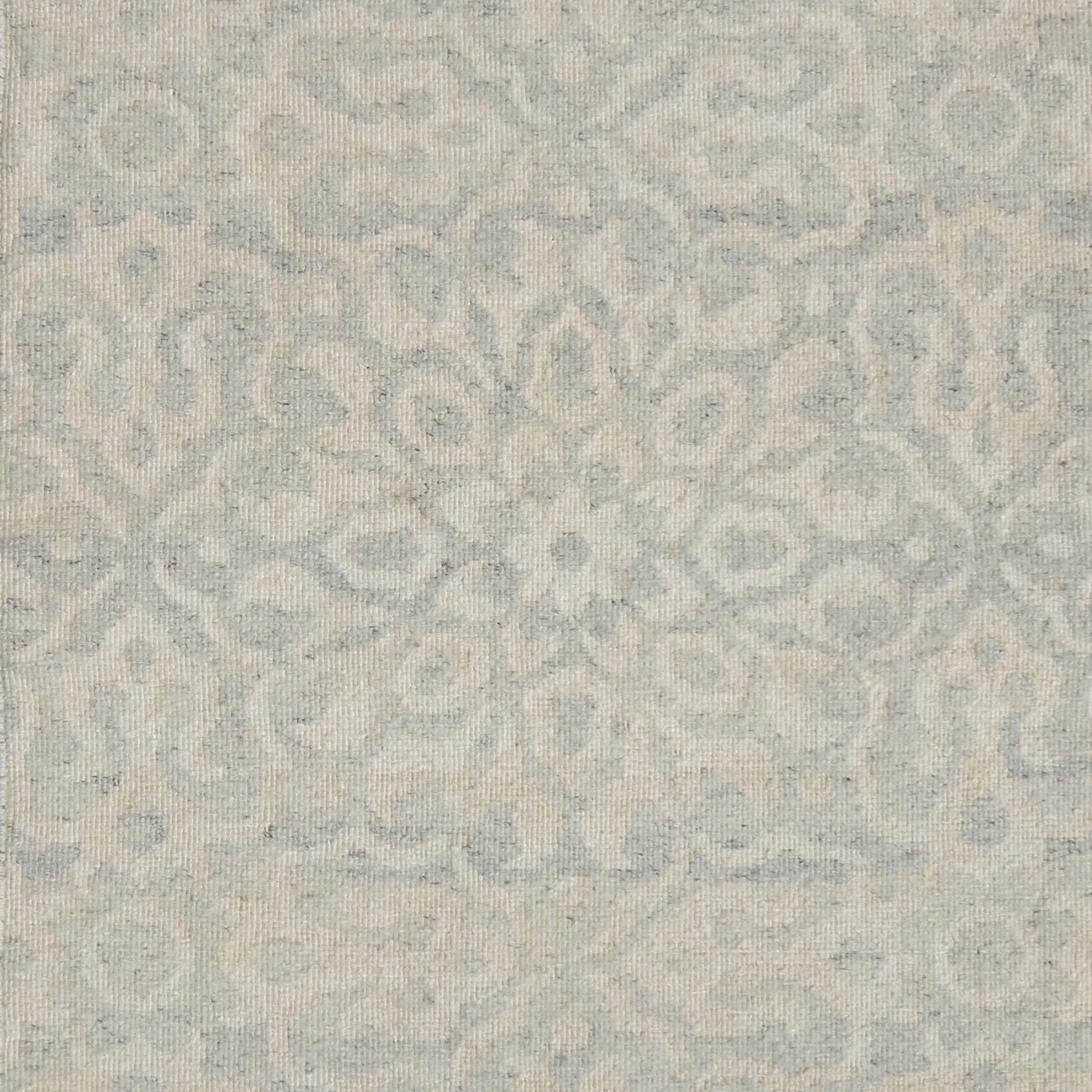 Close up of a handwoven rug in an ornate damask medallion design in cream on a grey field. 