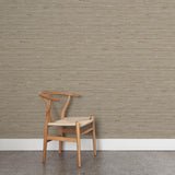 A wooden chair stands in front of a wall papered in a textural striped pattern in shades of tan and brown.