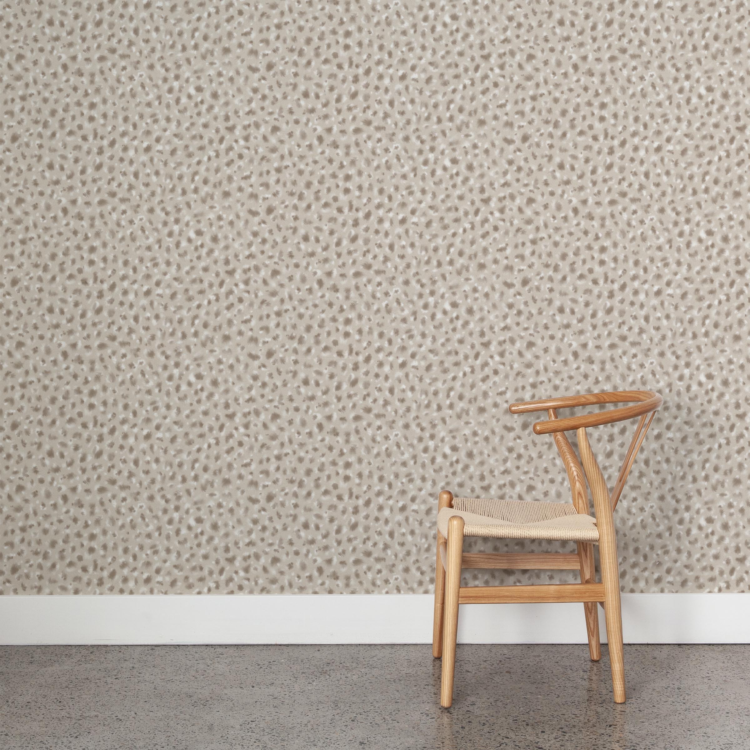 A wooden chair stands in front of a wall papered in a painterly animal print in white and brown on a sable field.