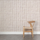 Wooden chair against wallpaper with watercolor plaid pattern in shades of brown.