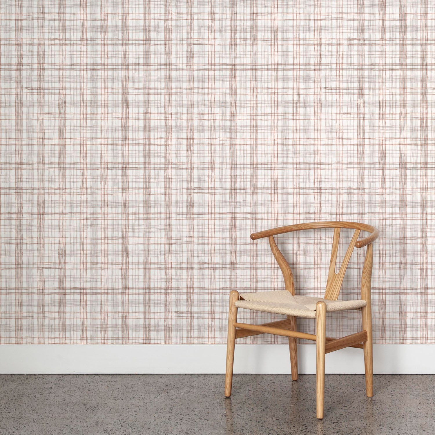 Wooden chair against wallpaper with watercolor plaid pattern in shades of rust brown. 
