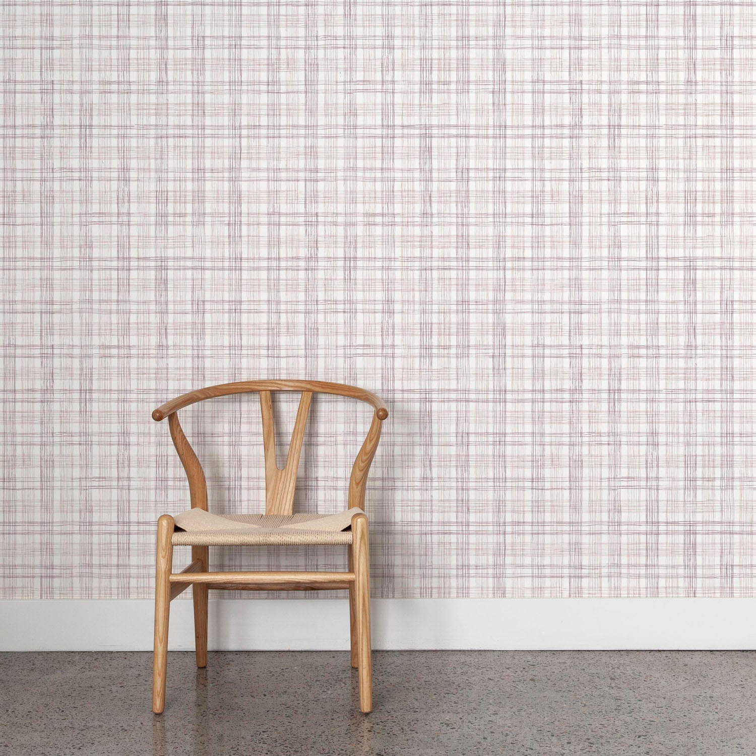 Wooden chair against wallpaper with watercolor plaid pattern in shades of mauve. 