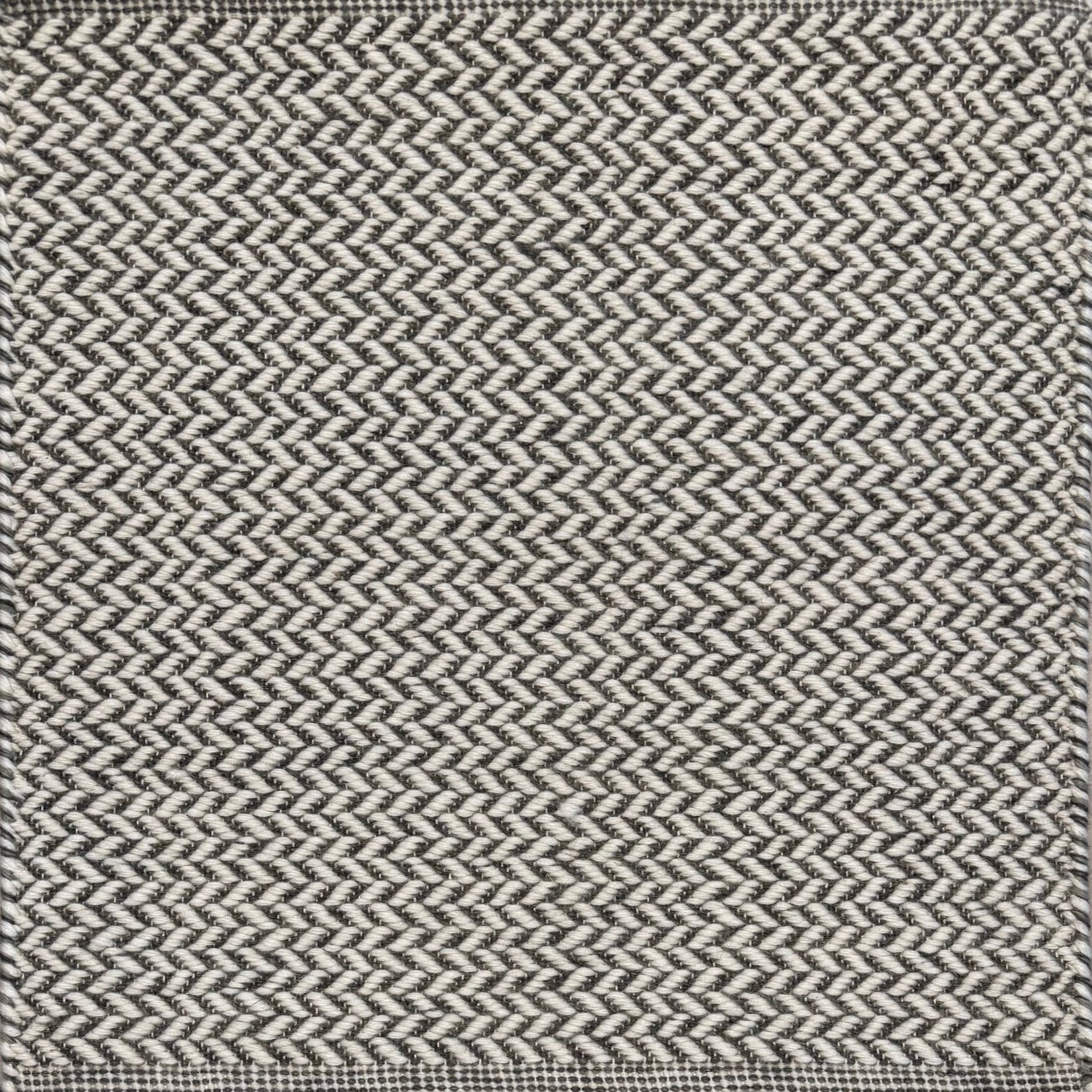 Textured rug with a herringbone pattern in white and dark grey.