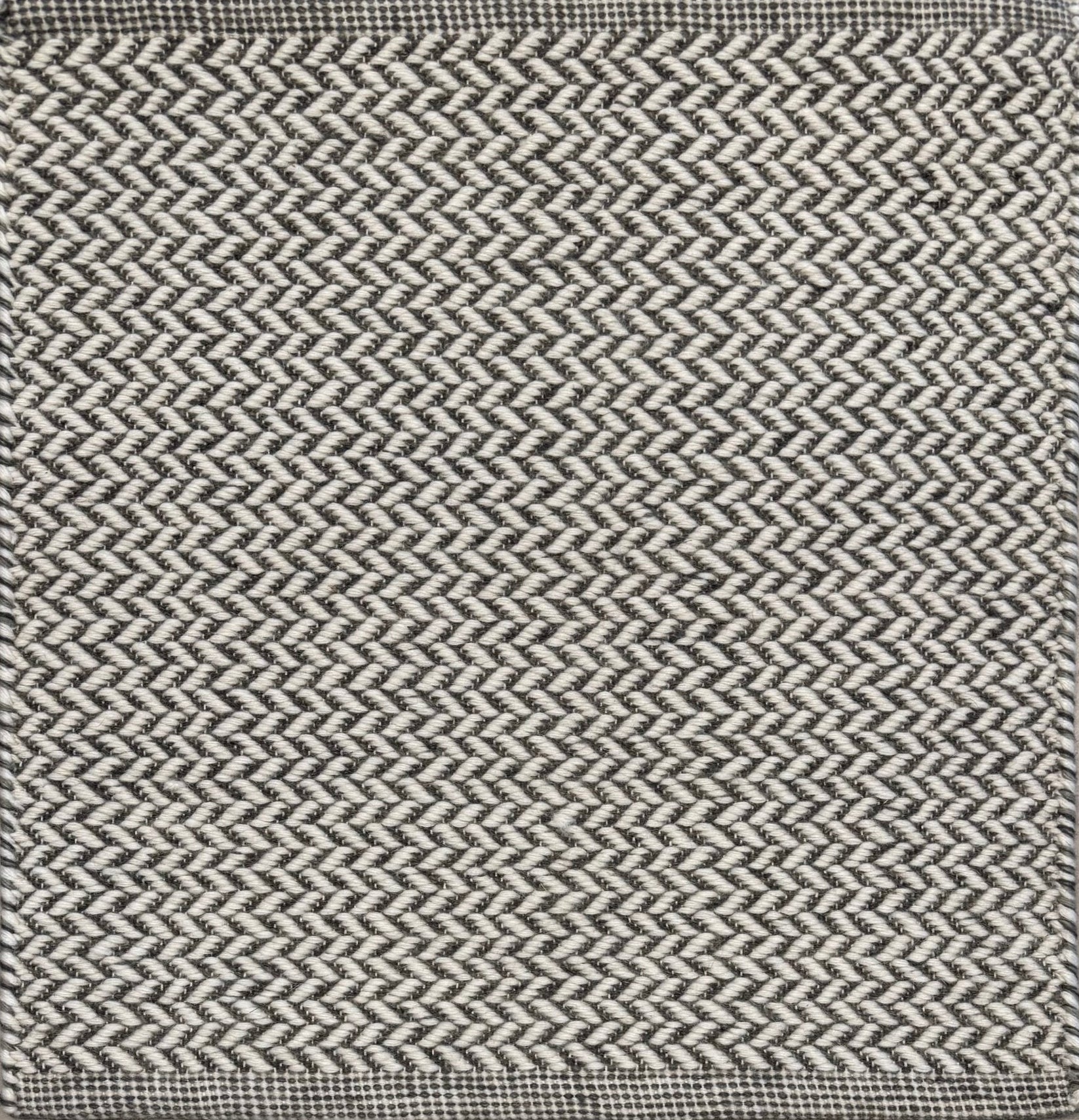 Textured rug with a herringbone pattern in white and dark grey.