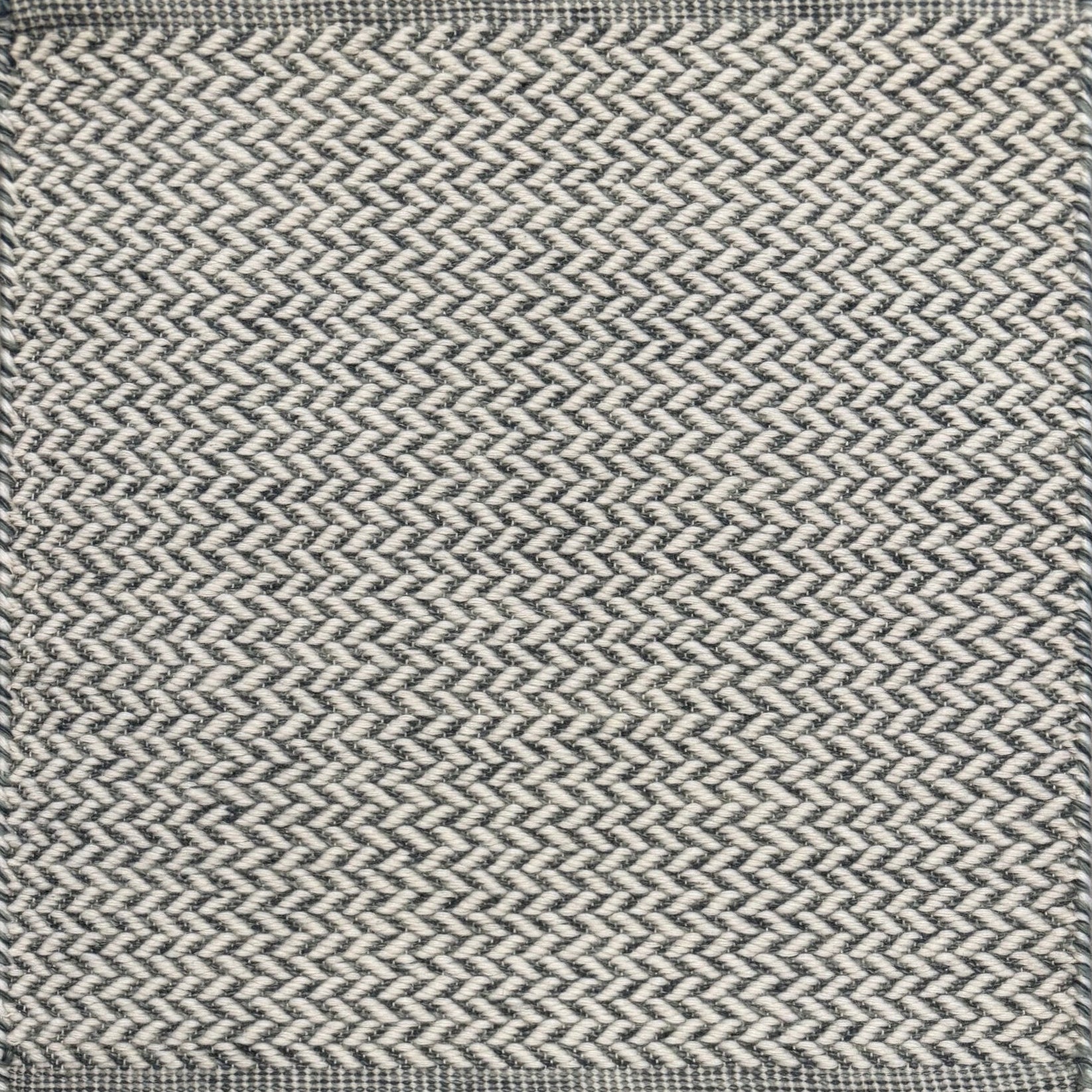 Textured rug with a herringbone pattern in white and slate blue. 