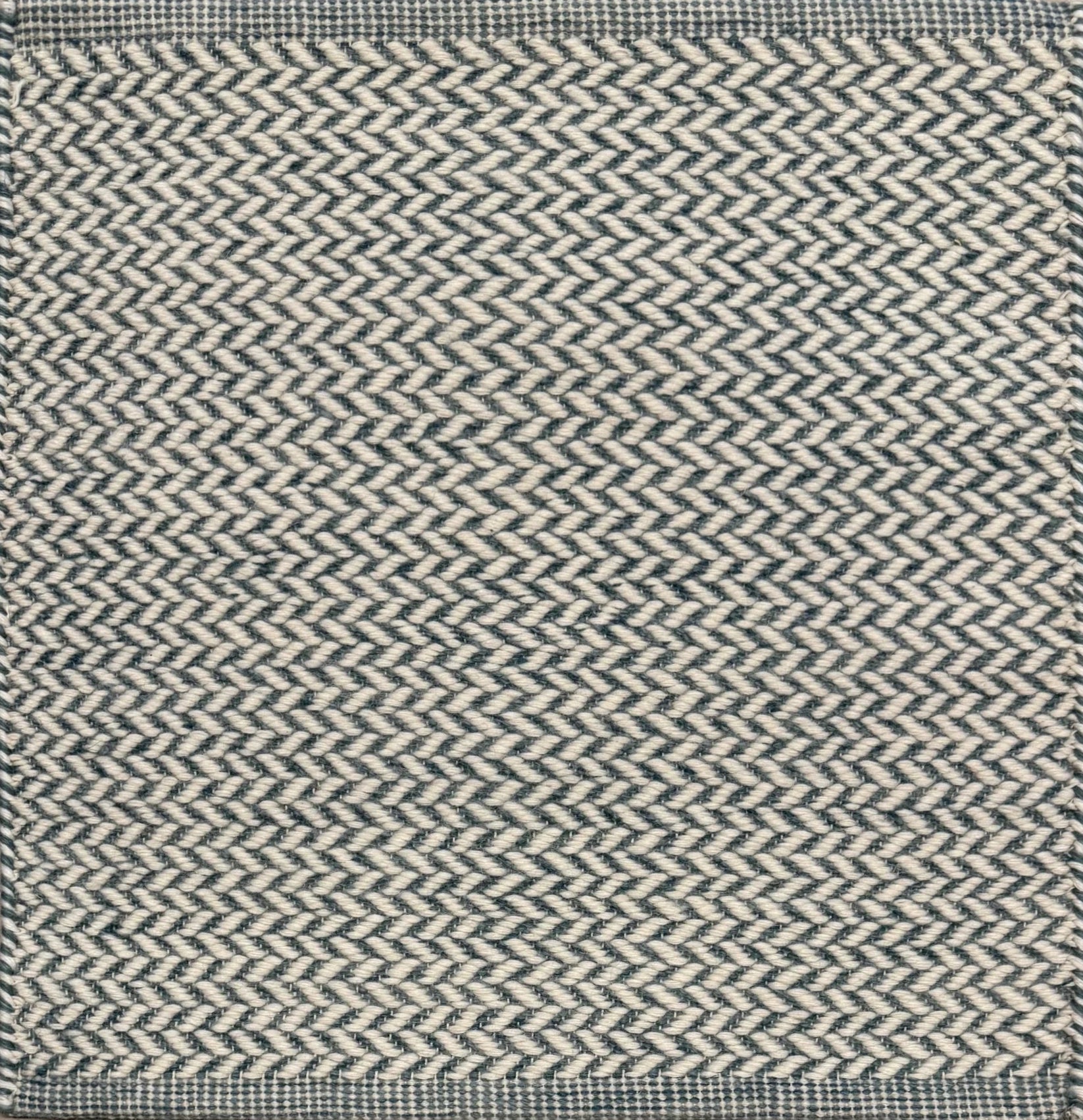 Textured rug with a herringbone pattern in white and teal.