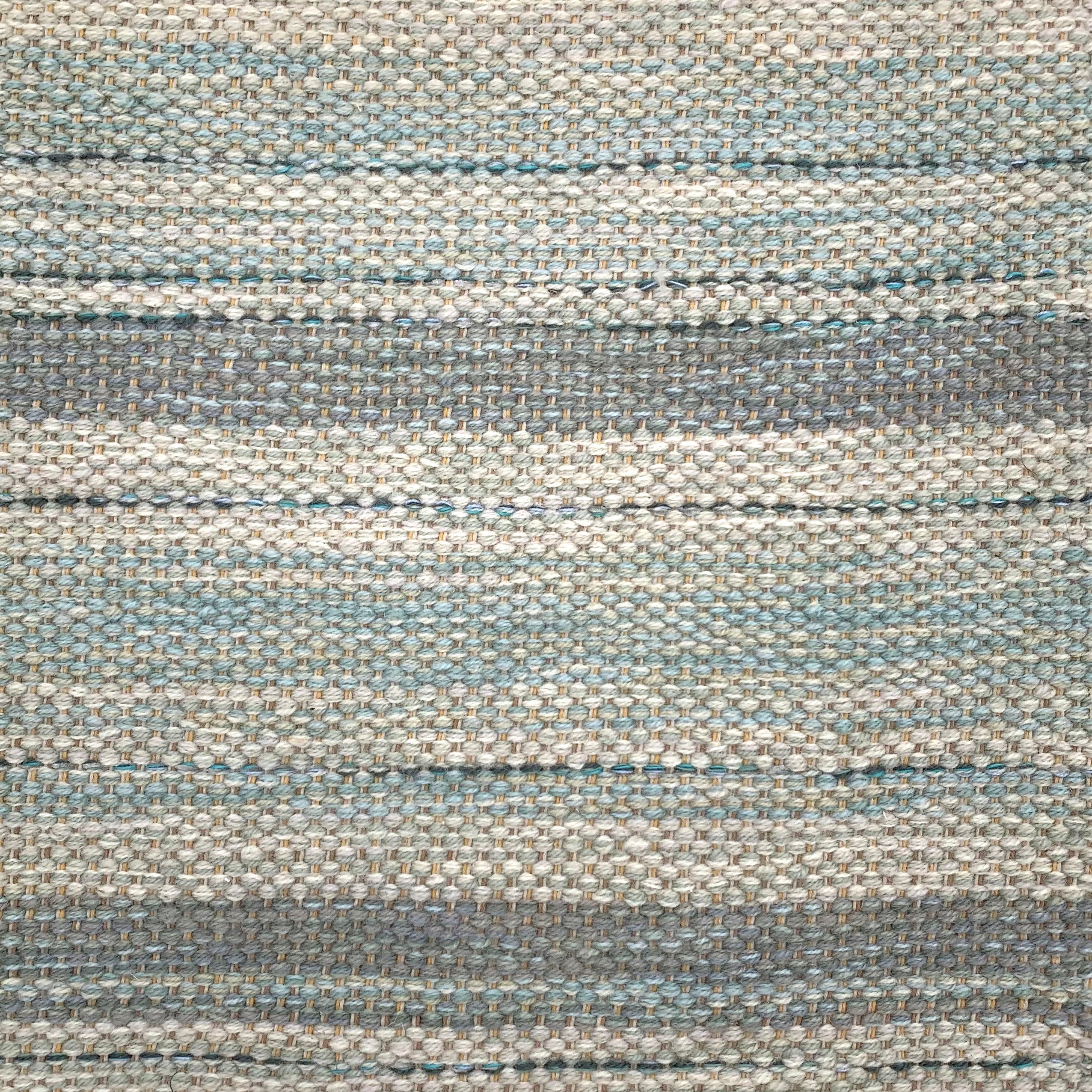 Handwoven rug detail in a stripe design in blue and grey 