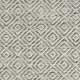 Detail of handwoven rug with diamond pattern in cream and shades of grey-blue.