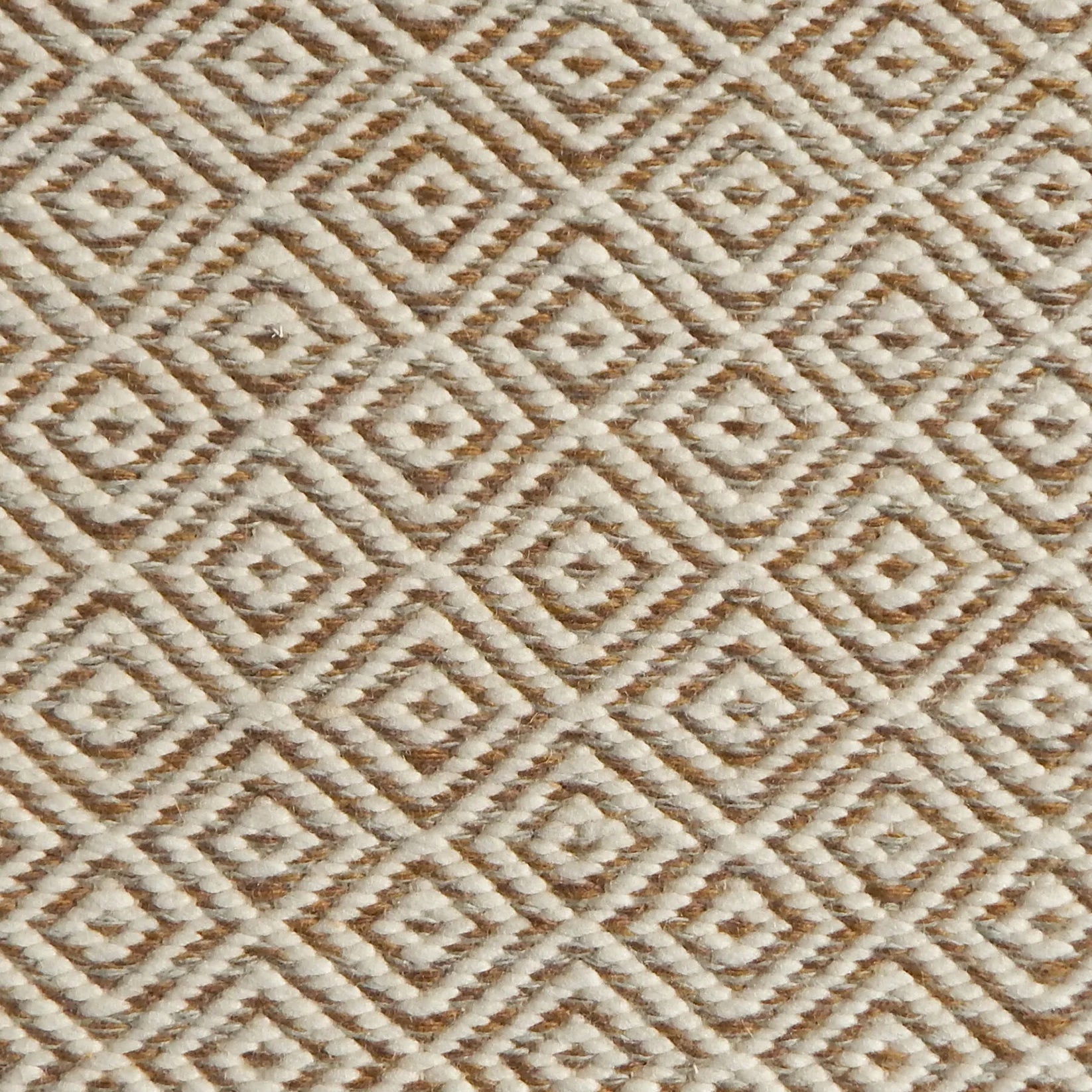 Detail of handwoven rug with diamond pattern in cream and shades of brown. 