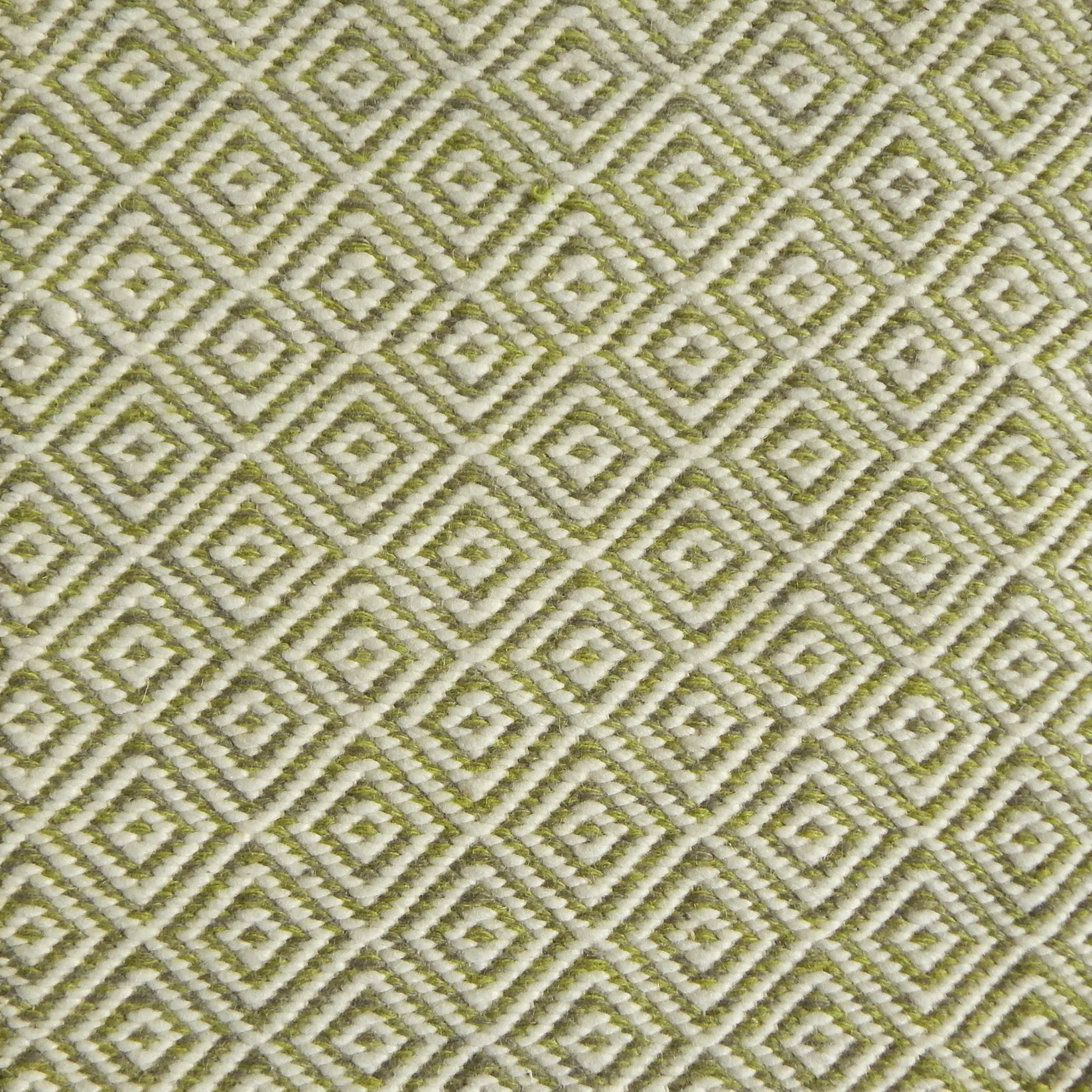 Detail of handwoven rug with diamond pattern in cream and lime green. 