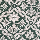 Close-up of fabric in a floral lattice print in white on a dark green field.
