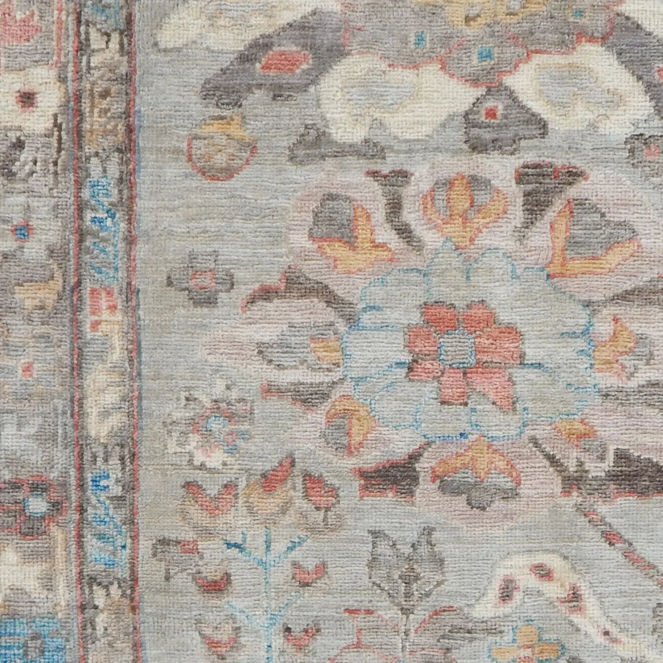 Close-up of a patterned rug with floral and animal designs on a gray background.