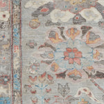 Close-up of a patterned rug with floral and animal designs on a gray background.