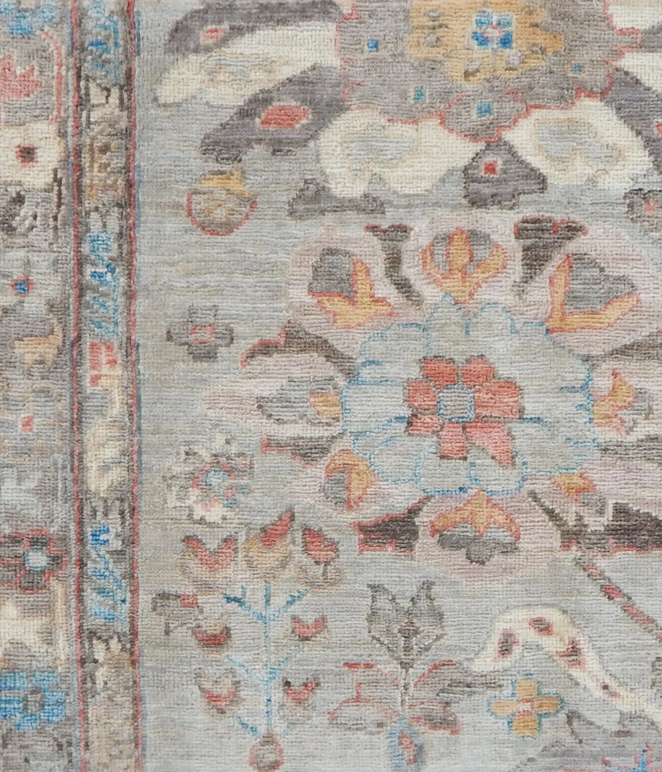 Close-up of a patterned rug with floral and animal designs on a gray background.